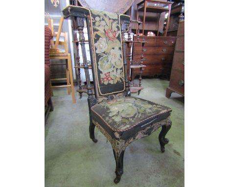 A Victorian prie dieu with ebonised frame and T shaped back with floral tapestry upholstery, raised on scrolled cabriole fore