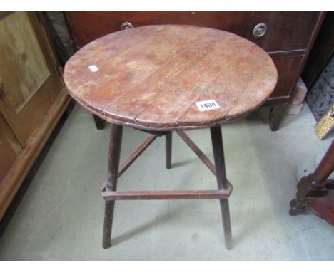 A small rustic country made cricket type table, the circular tongue and groove top raised on simple stick supports united by 