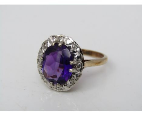 A 9ct ring set with a faceted amethyst within a diamond border, size M/N, 4g