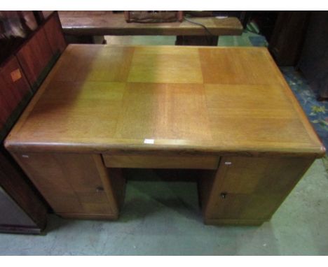 An Art Deco style light oak kneehole twin pedestal desk, each pedestal enclosed by two doors (one either side) with well matc