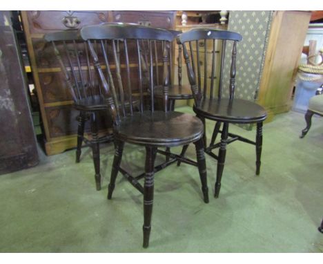 A set of four stained elm and beechwood Swedish stick back kitchen chairs with circular seats raised on ring turned and taper