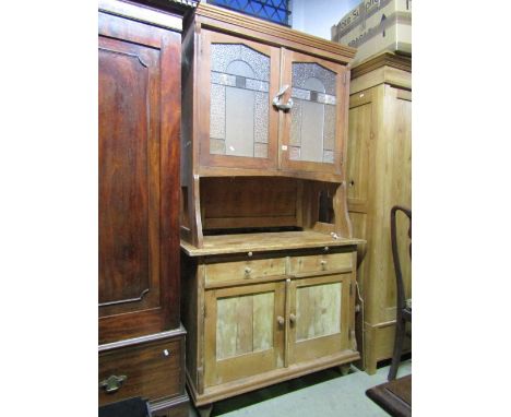 A vintage stripped pine kitchen dresser, the upper section enclosed by a pair of leaded light pointed arched panelled doors w