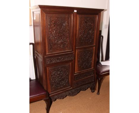A 19th Century Chinese hardwood cabinet, fitted four cupboards enclosed carved panel doors, two small drawers to side, on car