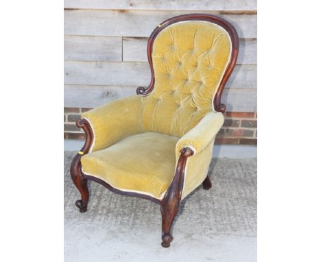 A Victorian mahogany  armchair, button upholstered in a gold velour, on scroll carved supports