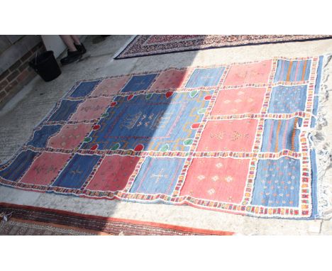 A Caucasian tribal rug decorated candlesticks on central blue ground panel surrounded by pink and blue squares with geometric