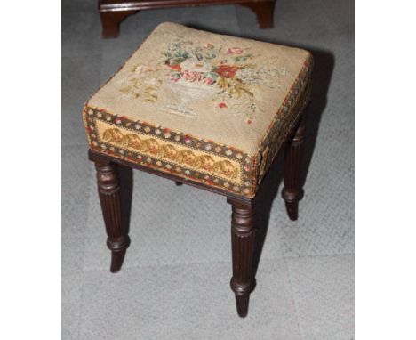 An early 19th Century mahogany stool with floral petit point upholstered seat, on turned and reeded supports