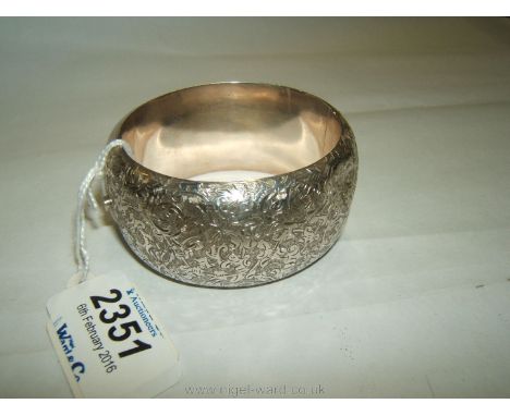 A wide unmarked white metal - possibly Silver Bangle with engraved decoration