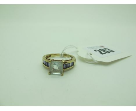 A QVC Modern 9ct Gold Dress Ring, square claw set to the centre, between channel set shoulders (finger size O) (3.5grams). 