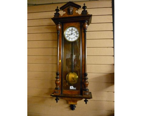 A walnut encased Vienna type wall clock, the white enamel dial set with Roman numerals with twin train striking movement, the