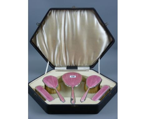 A hallmarked silver and pink enamel five piece dressing table set in a fitted case, Birmingham 1934 (some damage to mirror ha