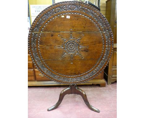 An 18th Century oak tilt top tripod table with later carving to the top, 75 cms high, 91 cms diameter top