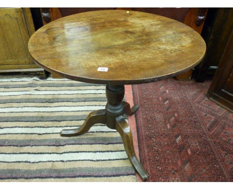 An antique oak circular tripod table with turned baluster support and 75 cms diameter top