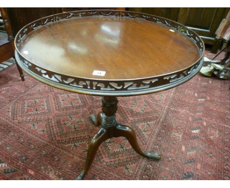 A mid to late 20th Century mahogany 65 cms diameter side table with gallery top, carved column supports and tripod base with 