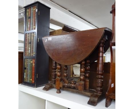 An oak oval drop leaf Gaelic table, on ring turned legs, and a narrow cabinet with a book design panel door (2) 