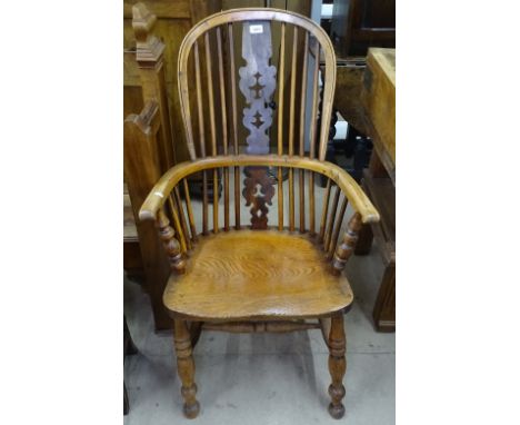 A 19th century yew wood and elm seated comb-back Windsor bow-arm chair, on turned legs 