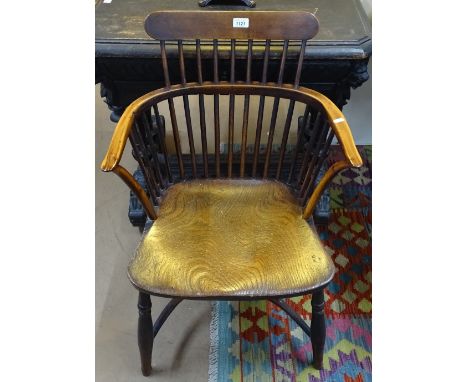 An early 19th century yew wood and elm comb-back Windsor elbow chair, with crinoline stretcher 