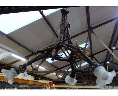 A ceiling light fitting made from stag's antlers, with glass shades, 31" across 