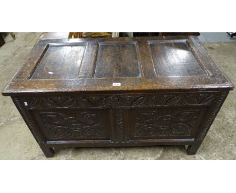 An 18th century joined oak coffer, with panel top, chip carved panel front, and raised on stile legs, W111cm 