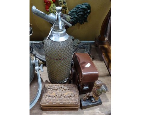 A soda syphon, a carved wood box, a figure, and a movie camera 