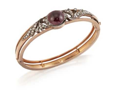 A GARNET AND DIAMOND BANGLE, a round carbuncle garnet within rose-cut diamond set scrolls, to a forked knife edge hinge openi