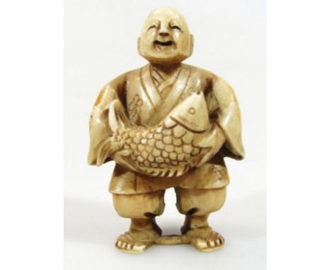 A 19thC Japanese Meiji period netsuke, formed as a standing figure in flowing part floral robes holding fish, two holes verso