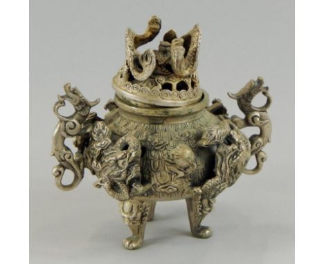 A Chinese white metal incense burner, heavily decorated with dragons, and having four character seal mark to the tripod base,