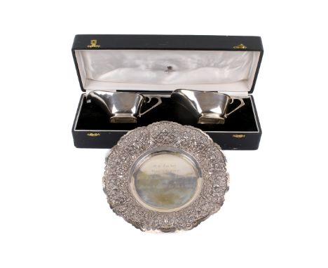 An Indian white metal presentation dish and a pair of sauce boats. The dish with repousse flower decoration marked 800 DELUX,