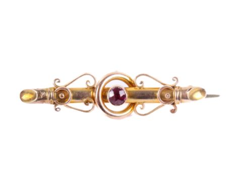 An early twentieth ceentury bar brooch with scroll motif. Set centrally with one round faceted pinkish red stone of 4.15mm di