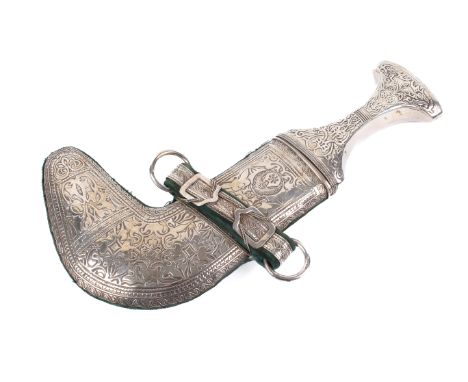 A Middle Eastern khanjar dagger. The white metal handle and scabbard decorated with ornamental patterns, backed by  green vel