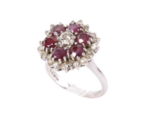 An 18ct white gold ruby and diamond cluster ring. Set centrally with one round brilliant cut diamond of 0.20 carats estimated