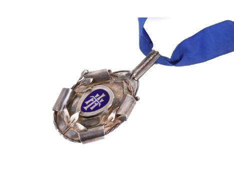 A vintage silver medallion. Having a blue enamel monogram to the centre, edged in flowers and scrolls, the verso engraved 'Pe