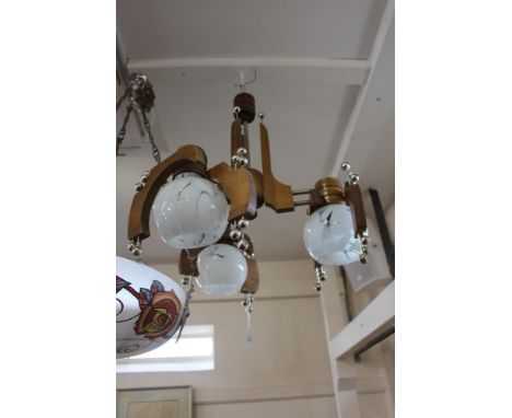 A wooden and chrome three branch pendant light fitting, with opaque cloudy glass shades