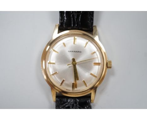 A gentleman's 1970's  yellow metal Garrard manual wind wrist watch, with case back inscription, on a leather strap, case diam