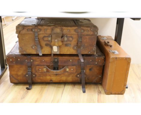 Three early 20th century brown leather cabin trunks and a later vintage suitcase, largest trunk 92cms wide x 52cms deep
