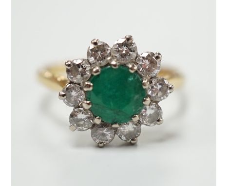 An 18ct, emerald and diamond set circular cluster ring, size K, gross weight 3 grams.