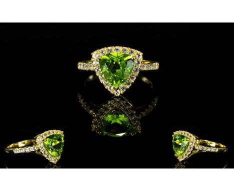 Peridot Trillion and White Topaz Ring, a 2.5ct trillion cut peridot of good colour, with .5ct of round cut white topaz framin