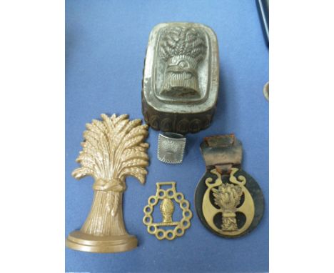 A mixed lot of wheatsheaf items, including a 19h century wheatsheaf jelly mould, a door stop, tie pin and horse brasses