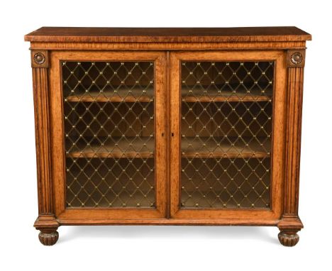 A William IV oak dwarf bookcase, the rectangular top above a pair of glazed and brass grilled doors enclosing adjustable shel