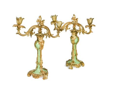 A pair of French style gilt metal and porcelain twin-branch candelabra, each of scrolling gilt work to a central green enamel