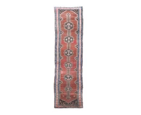 A Hamadan wool runner, circa 1930, the six pole medallions on a variegated madder ground417 x 107cmPile slightly low but even