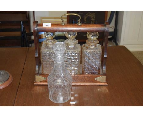 A vintage oak framed three bottle tantalus and a further decanter
