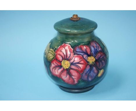 A Moorcroft table lamp of globular form on a green ground, decorated with a band of flowers, impressed mark, 16cm height