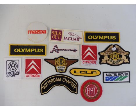 A quantity of sew on patches representing different motor cars and also for Harley Davidson.