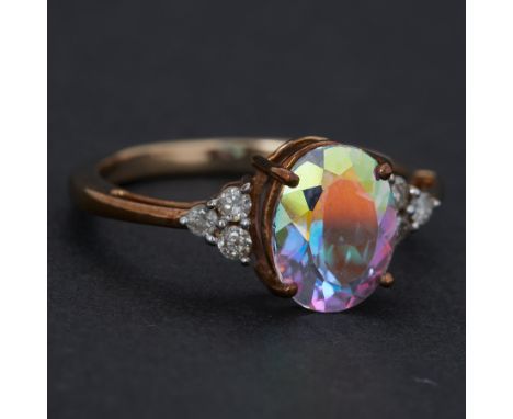 A 9ct yellow gold ring set with 3,13 carats of oval cut mystic topaz with a trefoil of round cut diamonds to each side, total