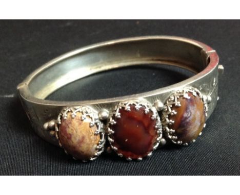 A Scottish agate and silver hinge bangle, three colour oval cabochons, each set within Gothic crown mounts, chased floral arc