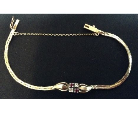 A diamond and ruby bracelet, two round brilliant cut diamonds and two conforming rubies crossed cube set within arching leaf 