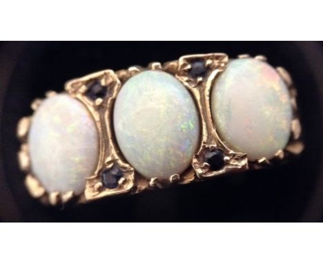 A seven stone opal and sapphire ring, three white oval opals separated by two pairs of  deep blue sapphires, scrolling wave m