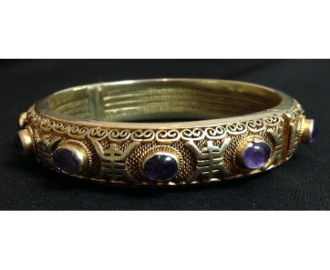 A silver gilt hinged bangle, the filigree body inset with twelve cabochon amethyst stones, stamped silver, 7cm diam, 43.1g gr