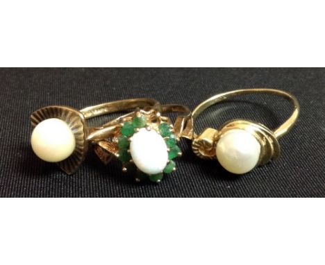 A cultured pearl dress ring, single creamy white pearl, rounded triangular shield back, 9ct gold shank; another; an emerald a