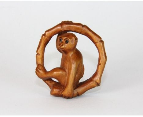 A carved wooden monkey in bamboo netsuke